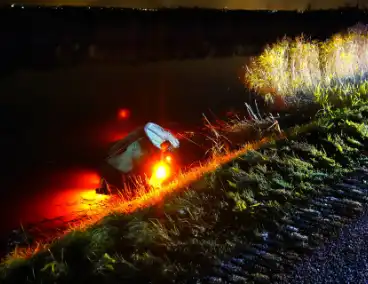 Twee auto's te water in bocht op gladde dijk