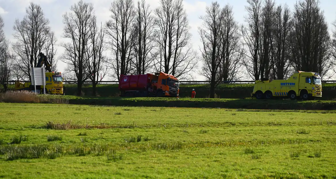 Vrachtwagen komt vast te zitten in weiland