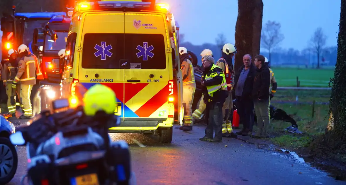 Auto op de kop na botsing met trekker en boom