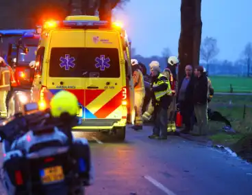 Auto op de kop na botsing met trekker en boom