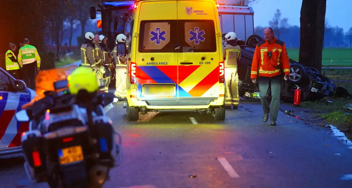 Auto op de kop na botsing met trekker en boom - Foto 2