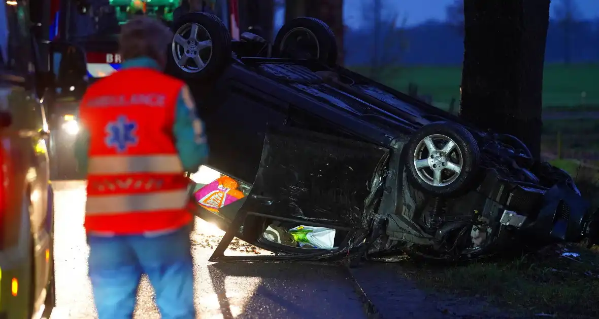 Auto op de kop na botsing met trekker en boom - Foto 4