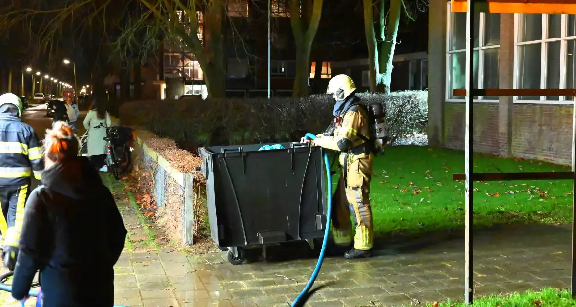 Brandweer blust brand in vuilcontainer