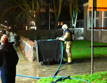 Brandweer blust brand in vuilcontainer