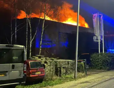 Vlammen slaan uit dak van gebouw