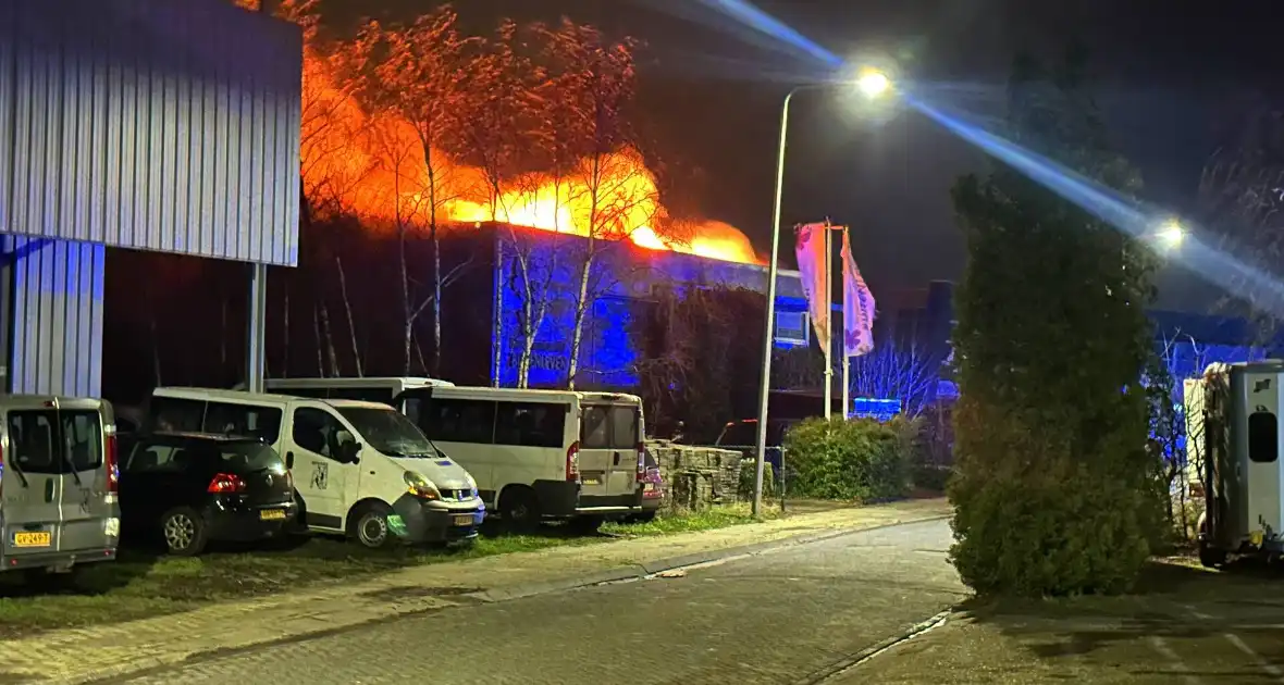 Vlammen slaan uit dak van gebouw - Foto 1