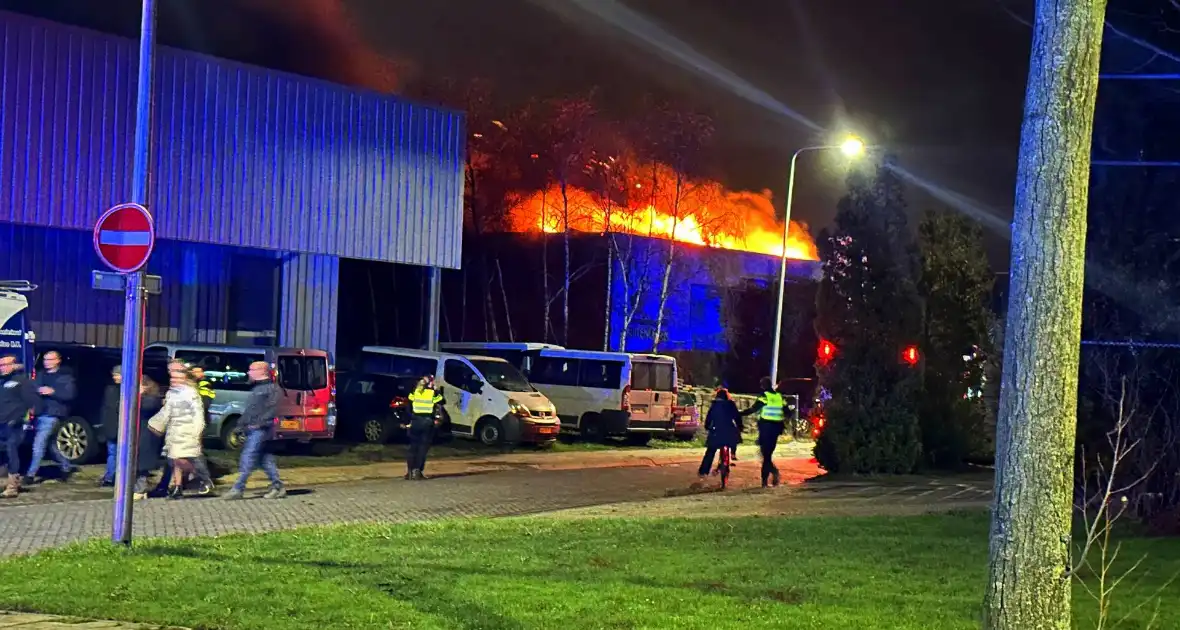 Vlammen slaan uit dak van gebouw - Foto 2