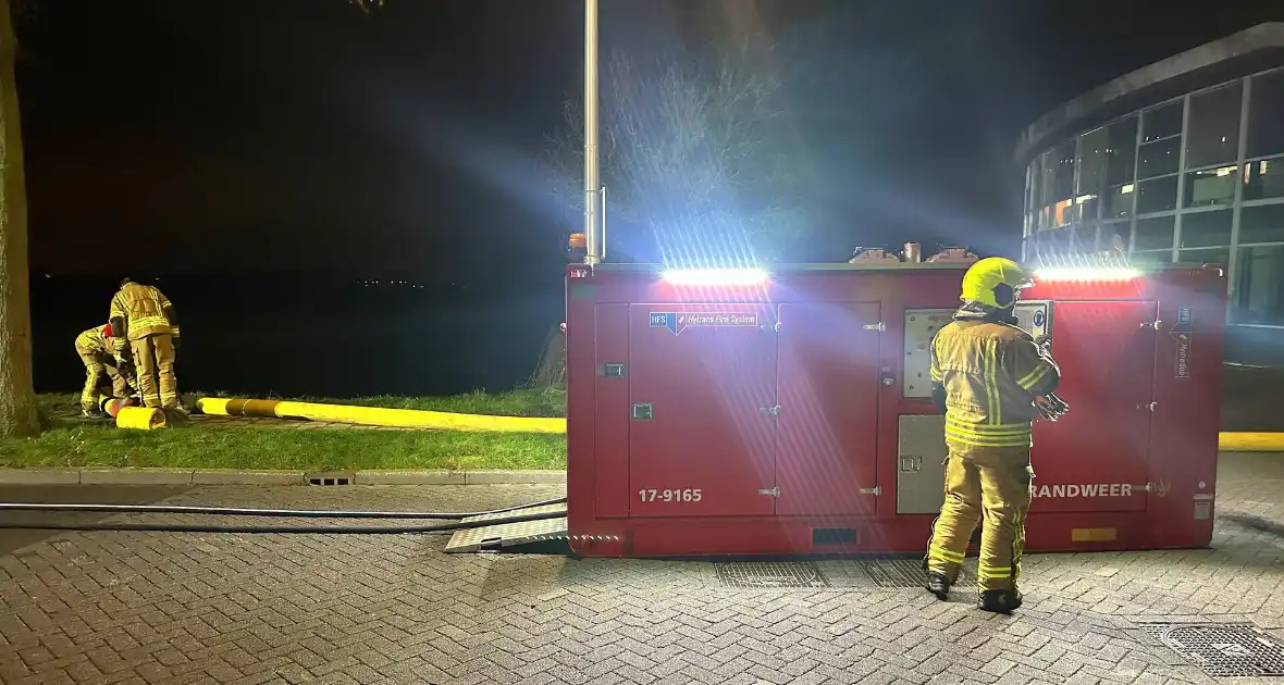 Vlammen slaan uit dak van gebouw - Foto 3