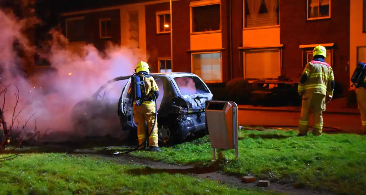 Auto in brand gestoken op grasveld