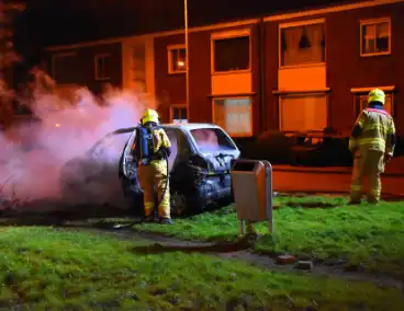 Auto in brand gestoken op grasveld