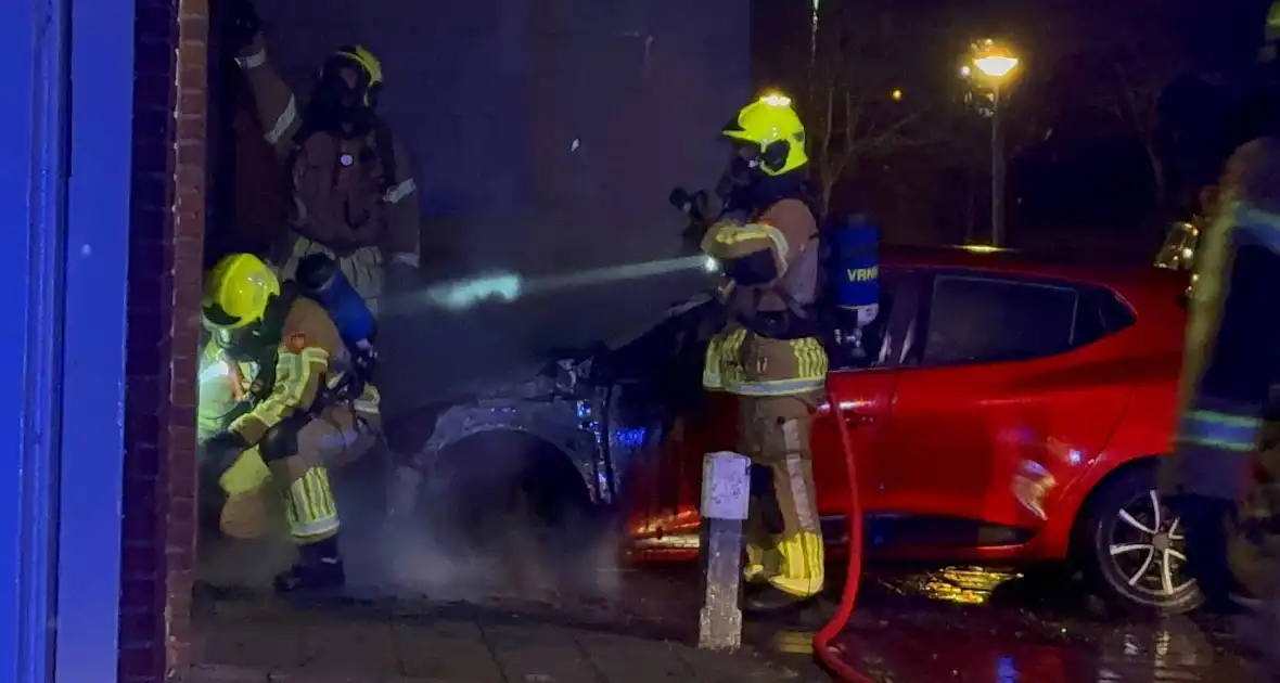 Auto brandt uit tegen gevel van flatgebouw - Foto 1