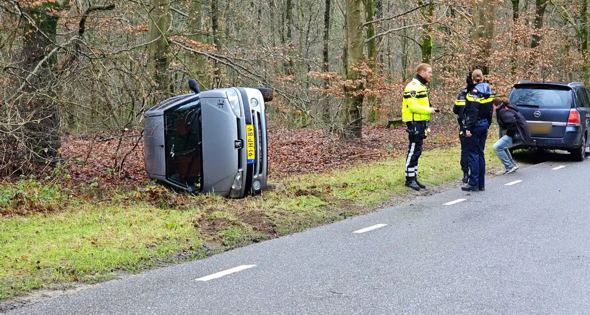 Auto belandt op zijkant naast weg