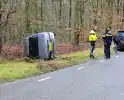 Auto belandt op zijkant naast weg