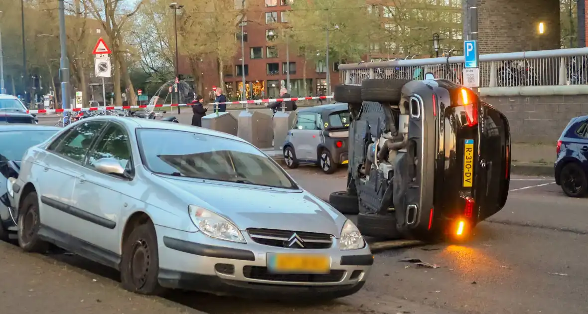 Auto botst op drie geparkeerde auto's en belandt op zijkant - Foto 3