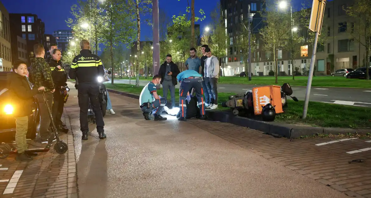 Maaltijdbezorger klapt tegen auto en komt ten val