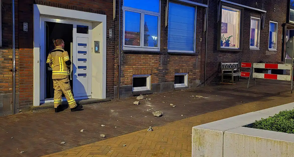 Brokstukken op stoep van gevel