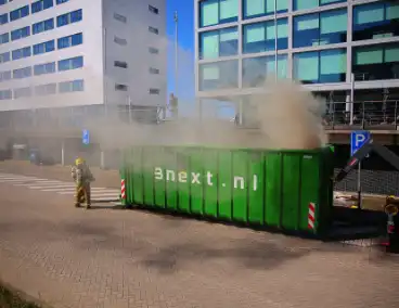 Vlammen slaan uit grote afvalcontainer