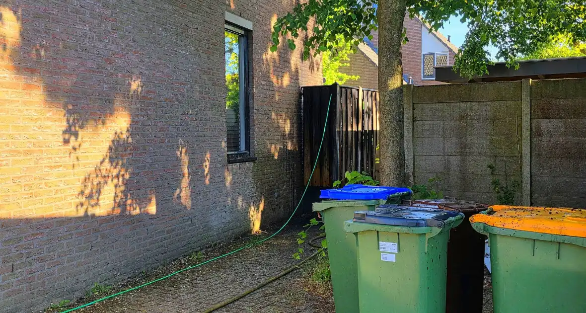 Schutting naast woning in brand