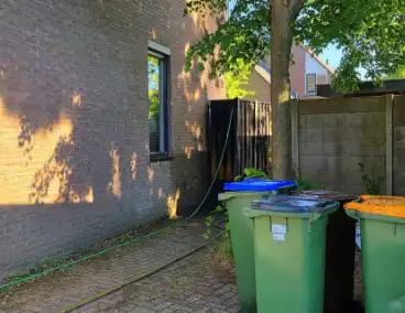 Schutting naast woning in brand