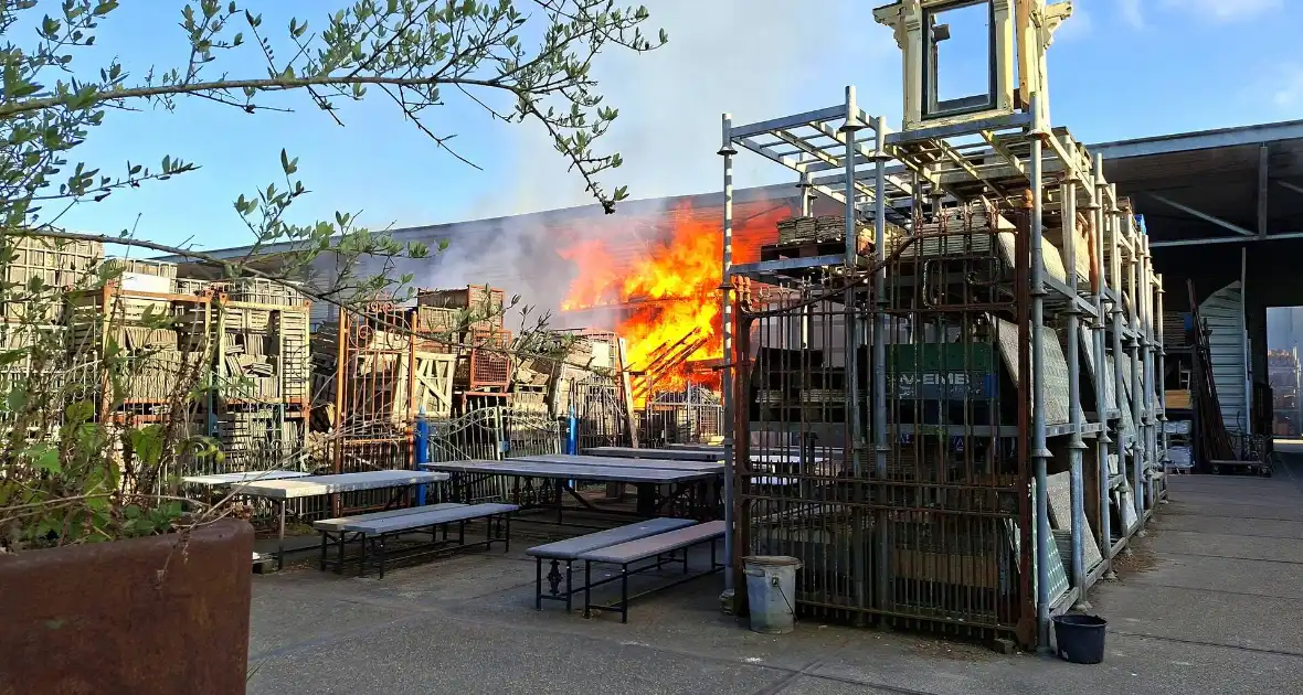 Palletopslag in brand, gebouw bedreigt