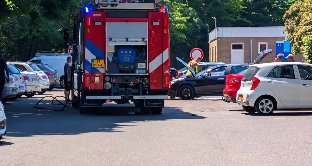 Brandweer blust auto op parkeerterrein
