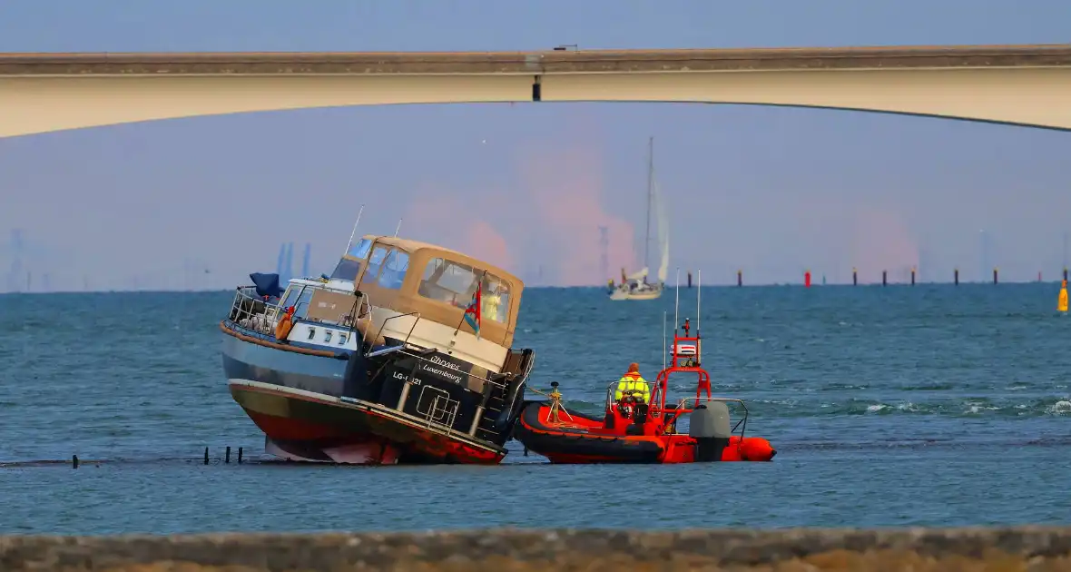 Boot loopt vast op dam, bergingsbedrijf schiet te hulp