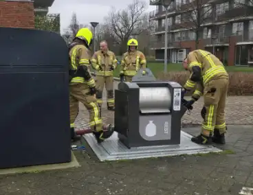 Container vat vlam door vuurwerk, omstanders doen bluspoging