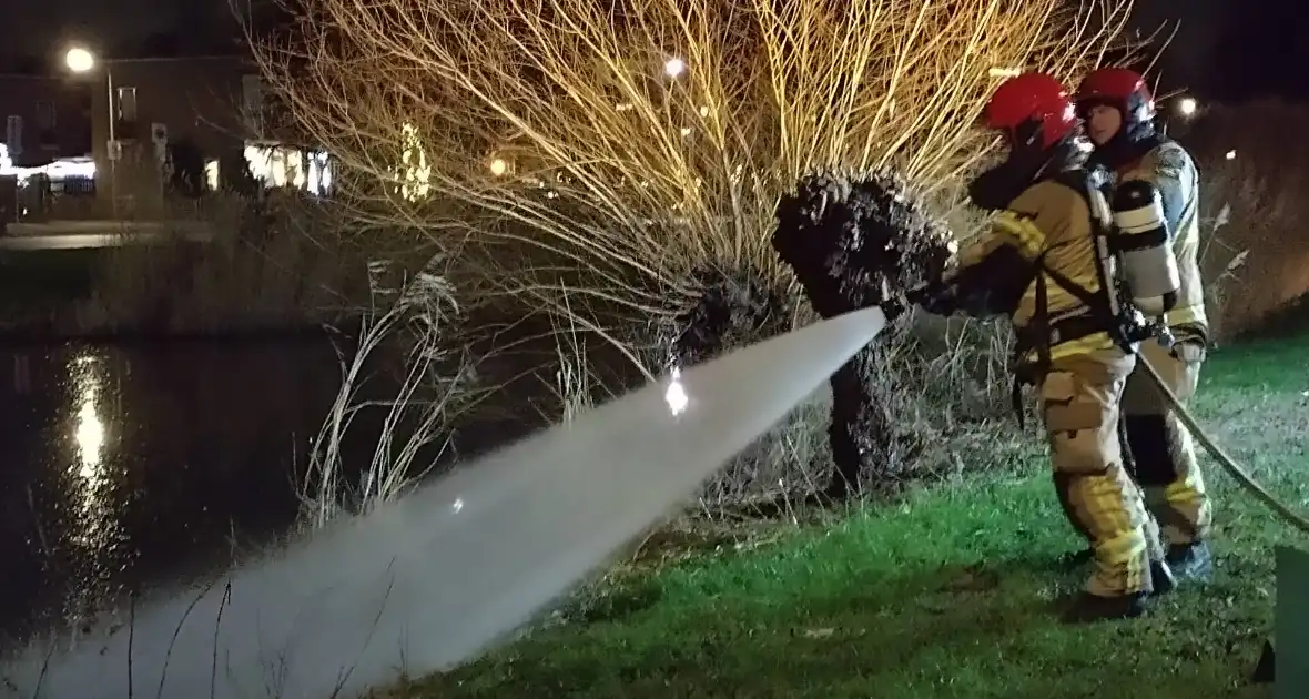 Brandweer blust brand langs sloot