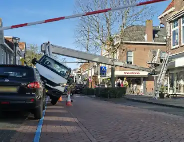 Hoogwerker kantelt tegen winkelpand