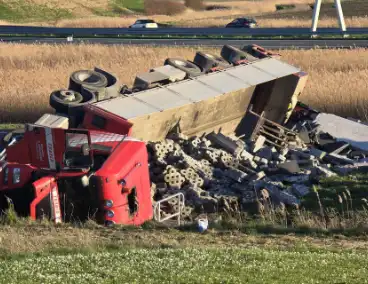 Vrachtwagen met betonblokken kantelt