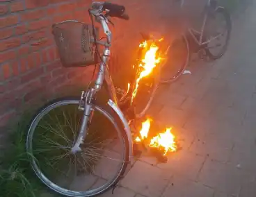 Fiets in brand tegen gevel van woning