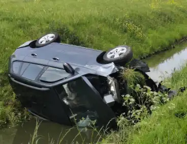 Auto belandt op zijkant in sloot naast snelweg