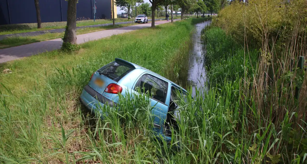 Omstanders halen inzittenden uit te water geraakt voertuig - Foto 5