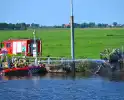 Tractor brandt uit langs waterkant, blusboot ingezet