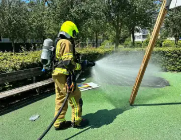 Brandend kunstgras geblust door brandweer