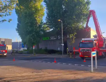Brand in boom en bosschages naast bedrijfspand