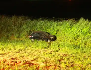 Auto raakt van dijk en belandt in riet