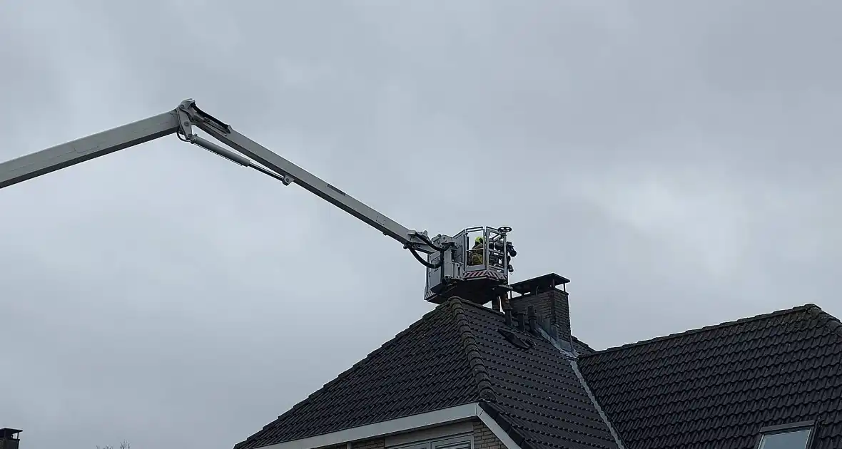 Brandweer verwijderd losse plaat op schoorsteen van woning - Foto 1