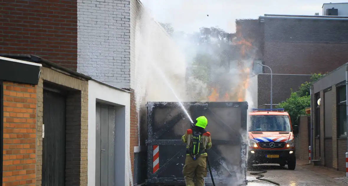 Vlammen slaan uit bouwcontainer met afval - Foto 1